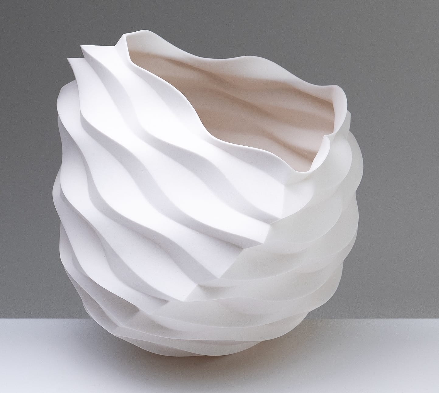 an abstract, white porcelain sculptural vessel loosely resembling intricately folded paper
