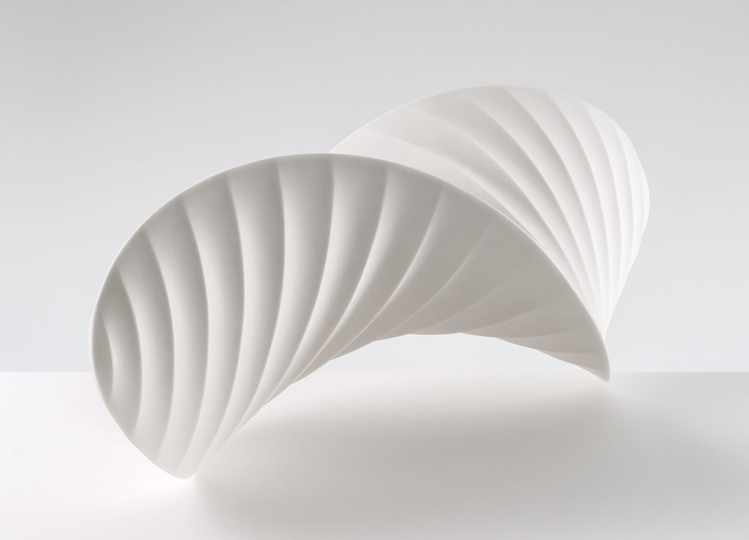 an abstract, white porcelain sculpture loosely resembling intricately folded paper