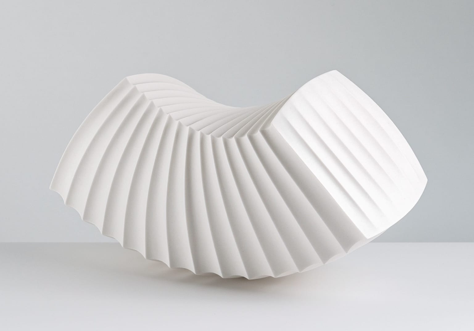 an abstract, white porcelain sculpture loosely resembling intricately folded paper