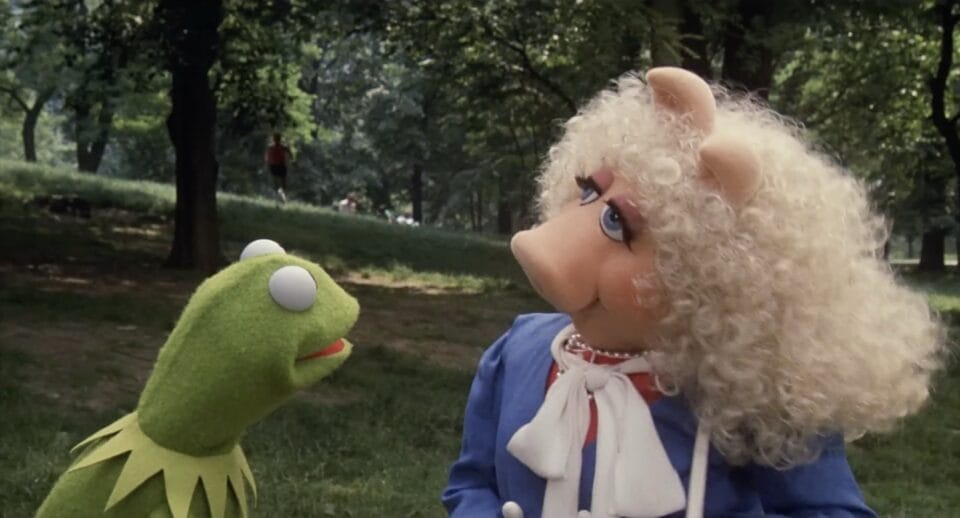 a still from a Muppet film showing Kermit the Frog and Miss Peggy talking outside