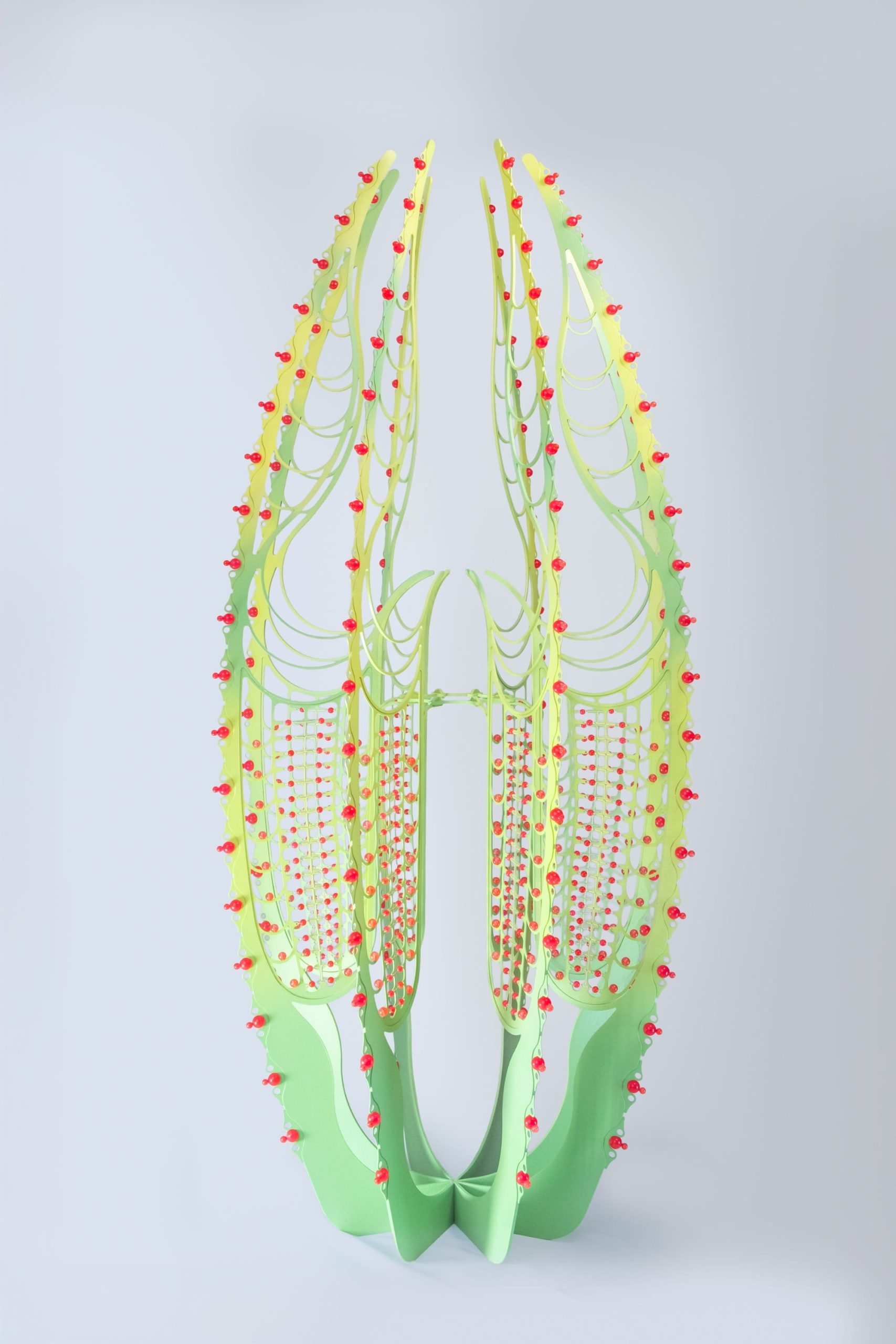 a tall green curved sculpture with red beads on the sides