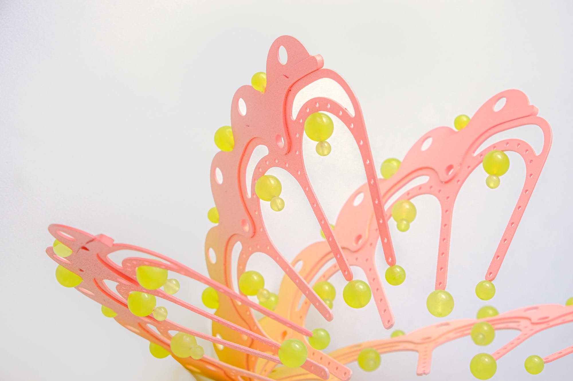 detail of a pink and yellow curved sculpture with scalloped edges