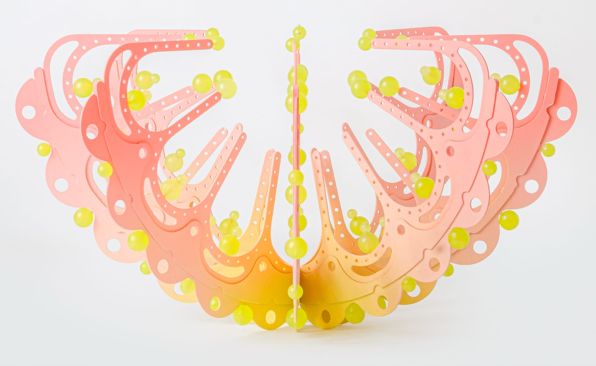 a pink and yellow curved sculpture with scalloped edges