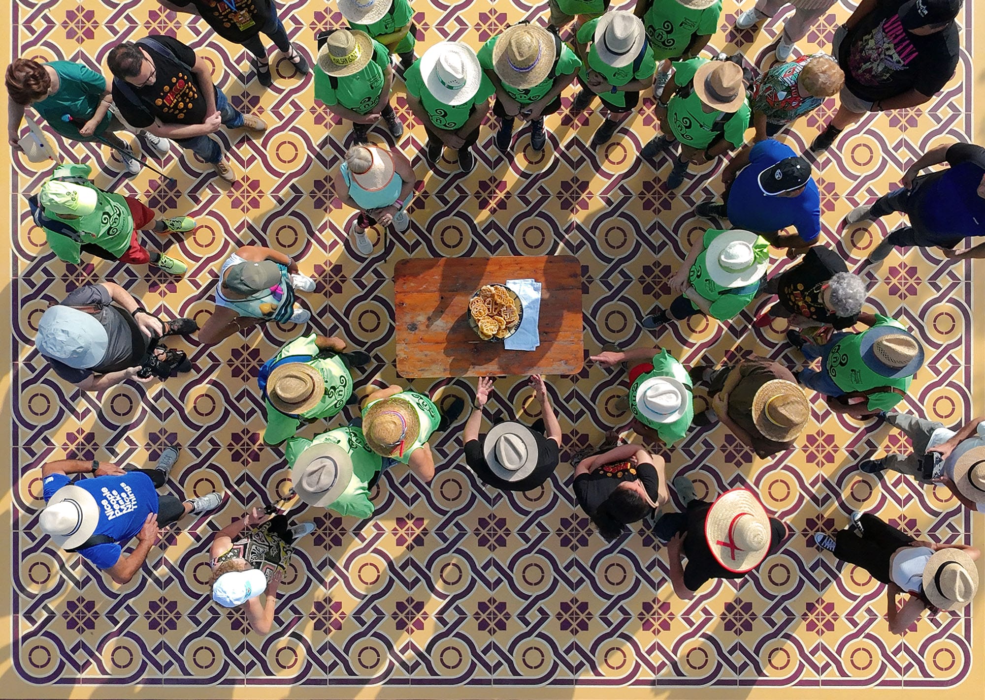 an aerial view of people gathering on a red and yellow mural