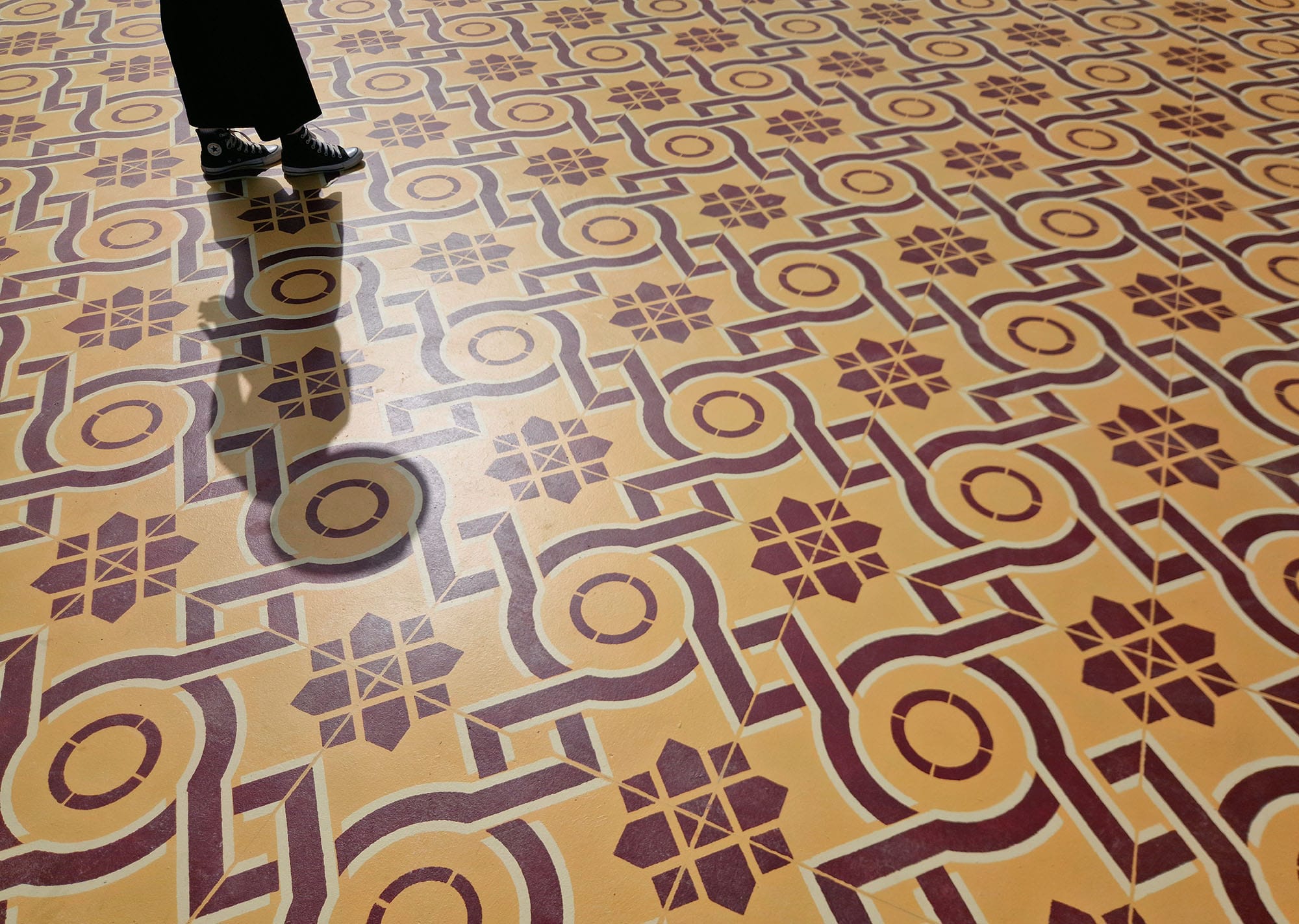 a detail of a red and yellow patterned rug with a person walking on it