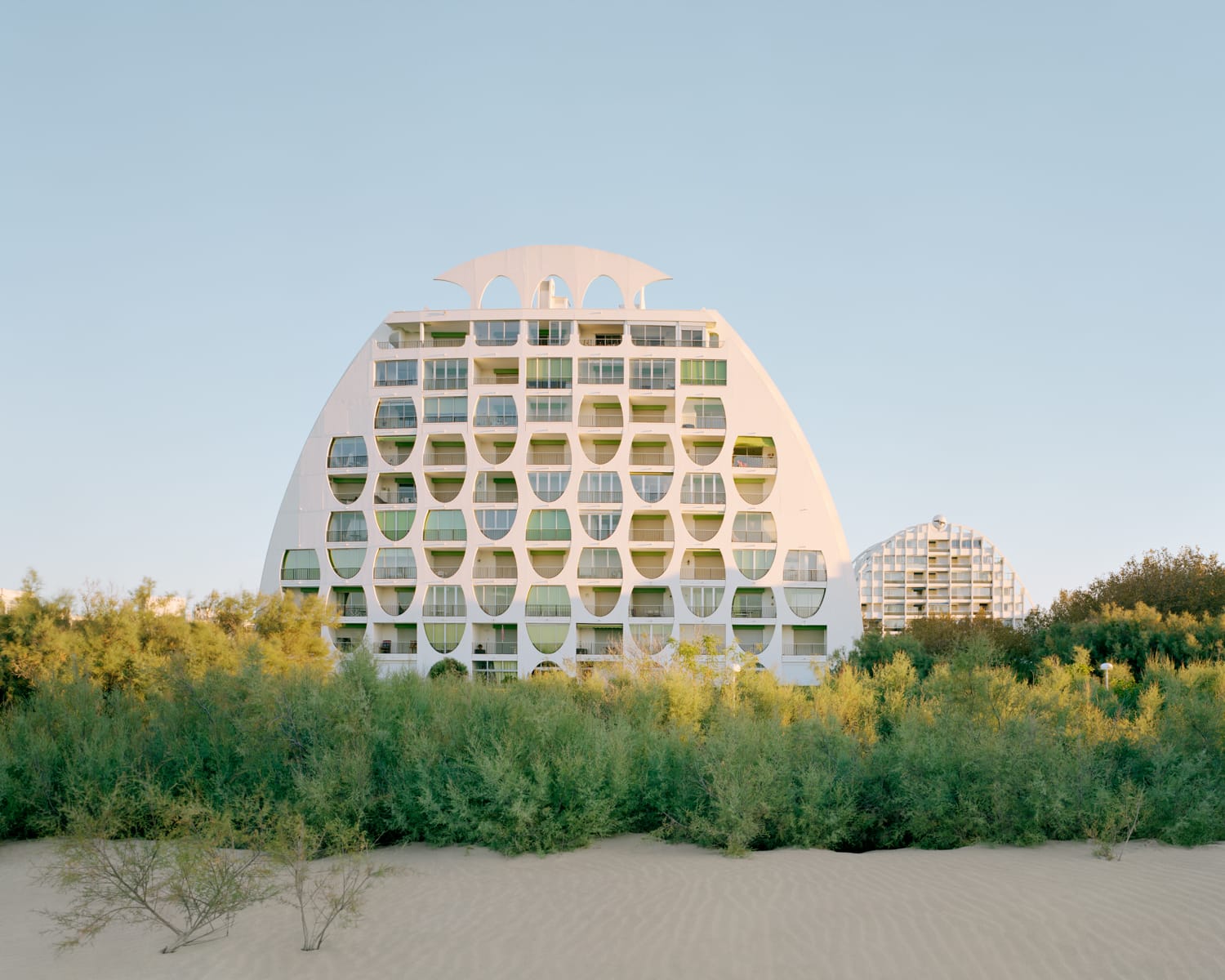 a modernist resort apartment complex in all-white against a blue sky