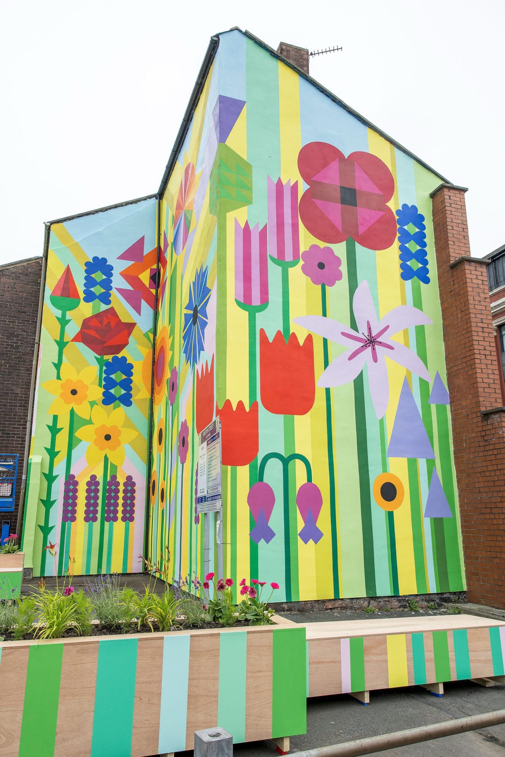 a vibrant floral and geometric mural around the corner of a brick building