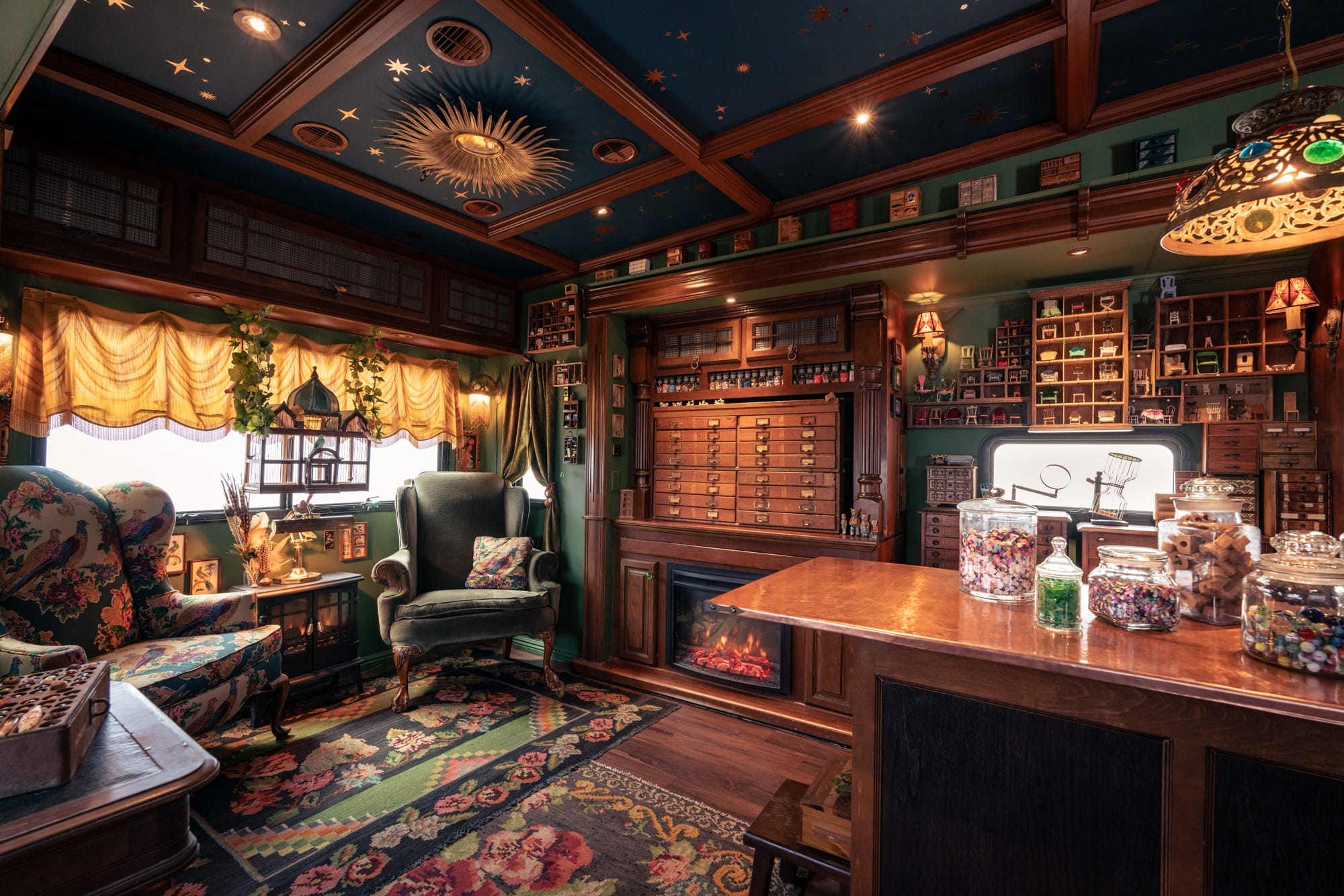 the moody wood and soft seating interior of a traveling museum with cabinets, jars, and lots of storage
