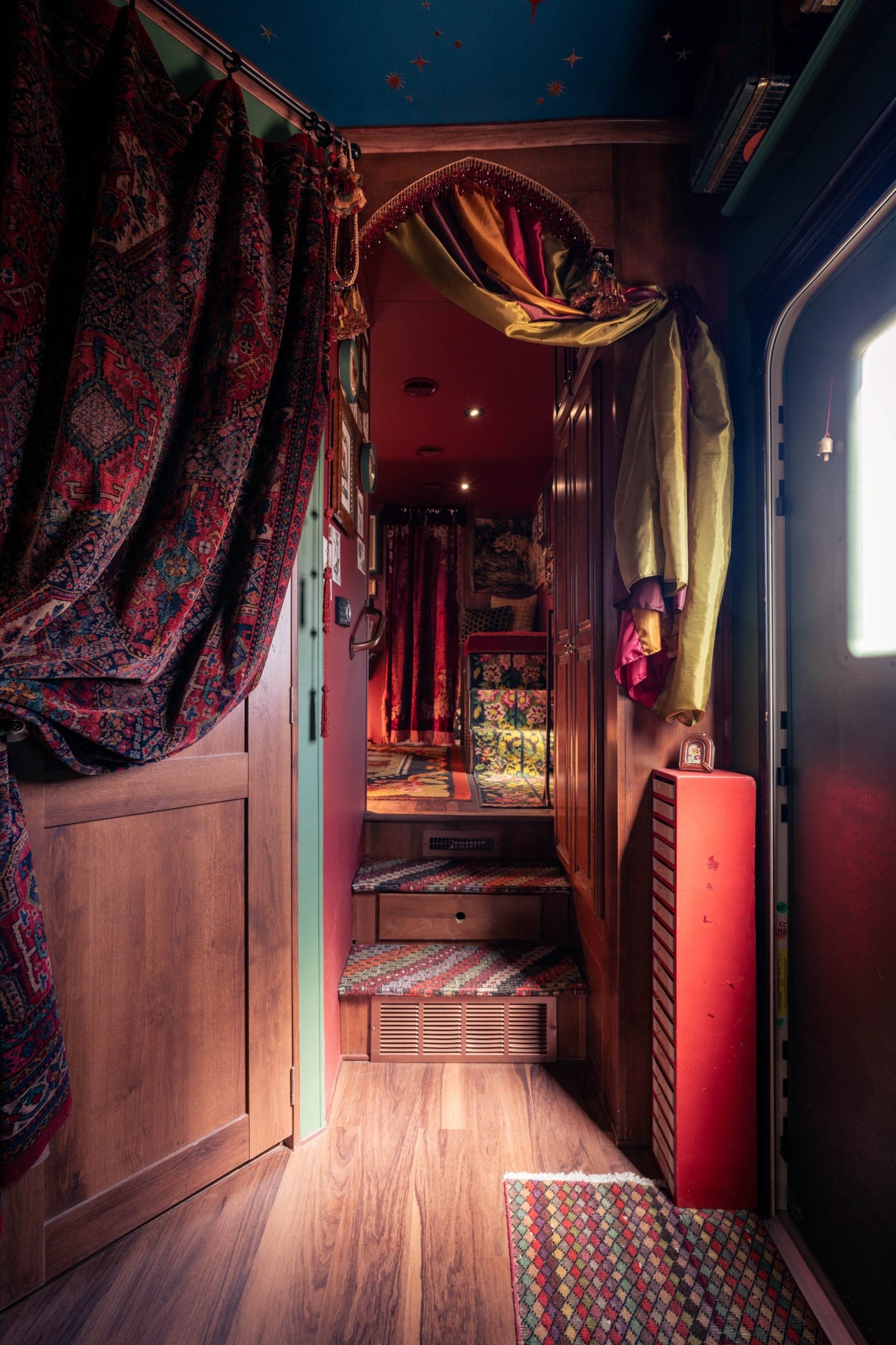 the moody wood and soft seating interior of a traveling museum with cabinets, jars, and lots of storage