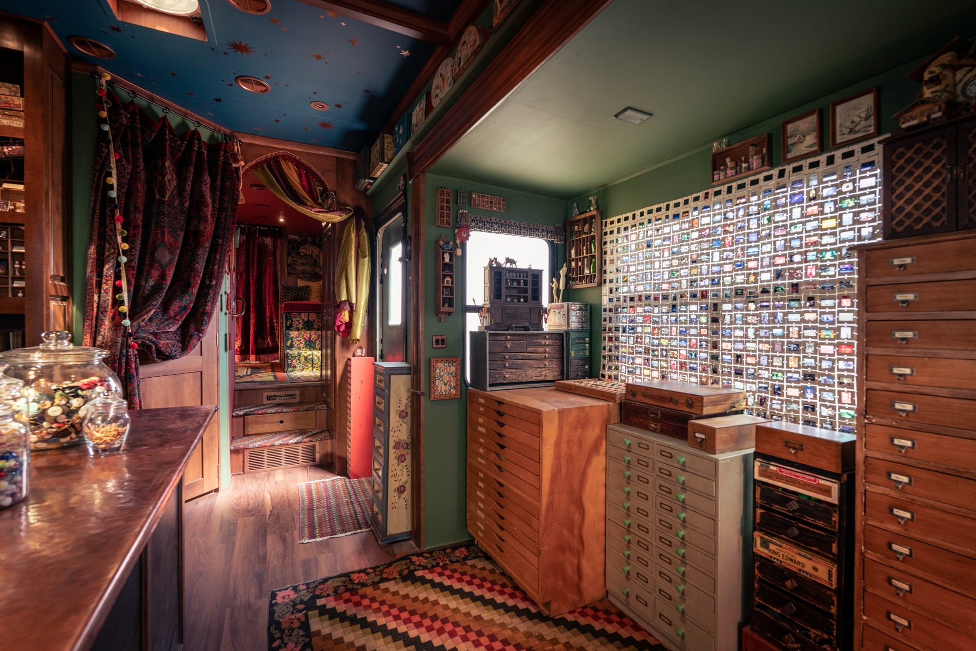 the moody wood and soft seating interior of a traveling museum with cabinets, jars, and lots of storage