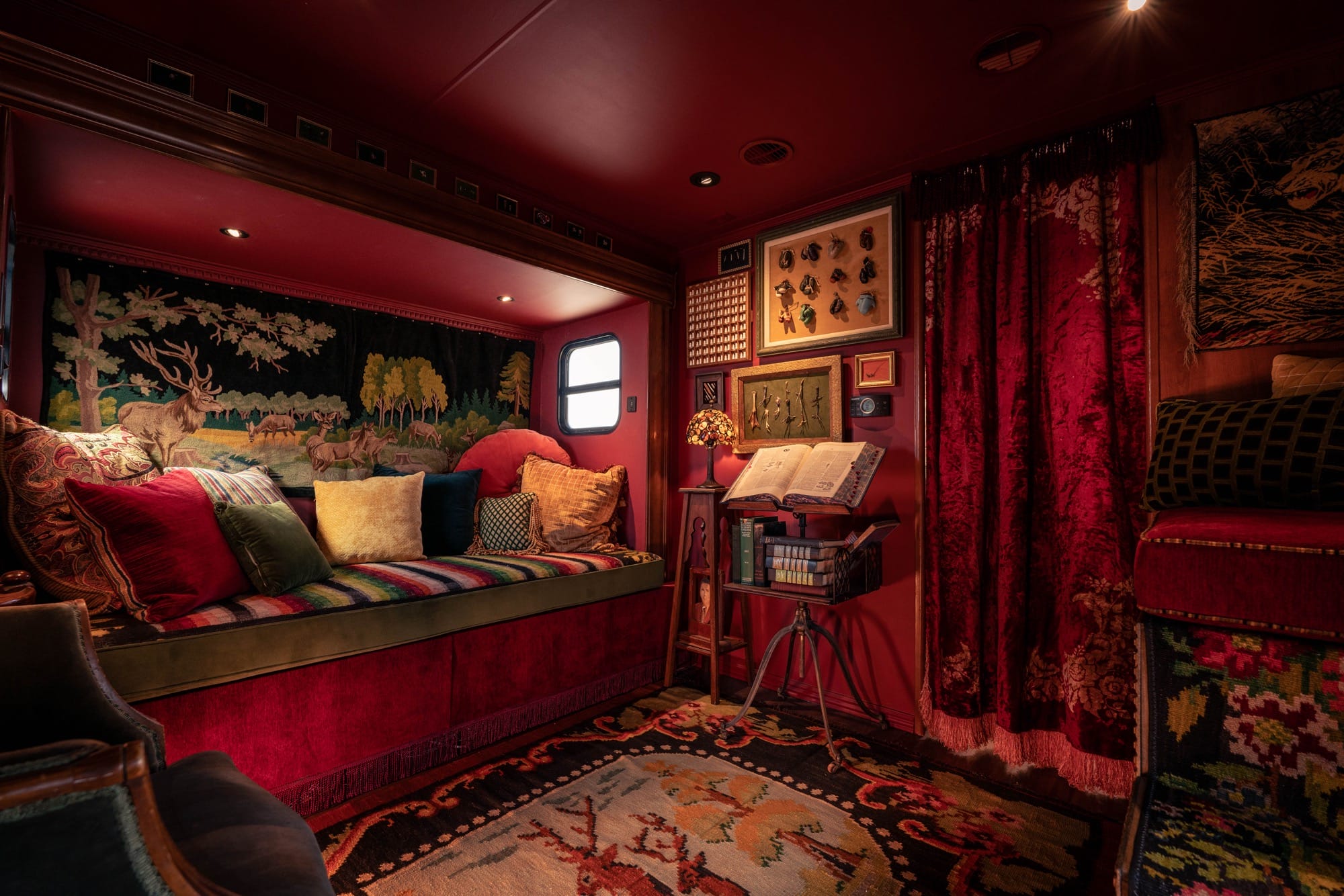 an interior with red walls, a daybed, and displays on the wall