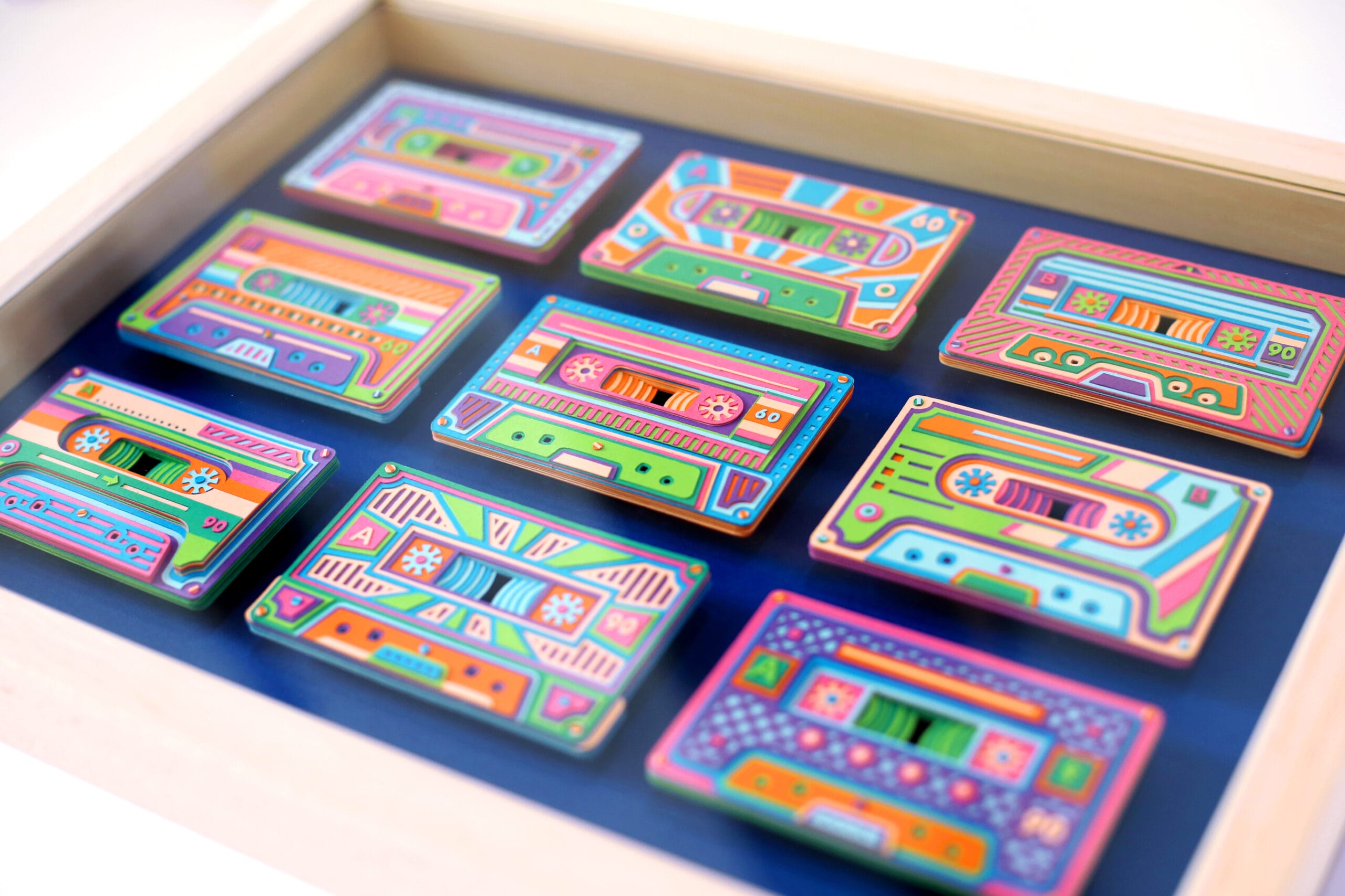 a set of colorful cassette tapes made from paper, in a white frame