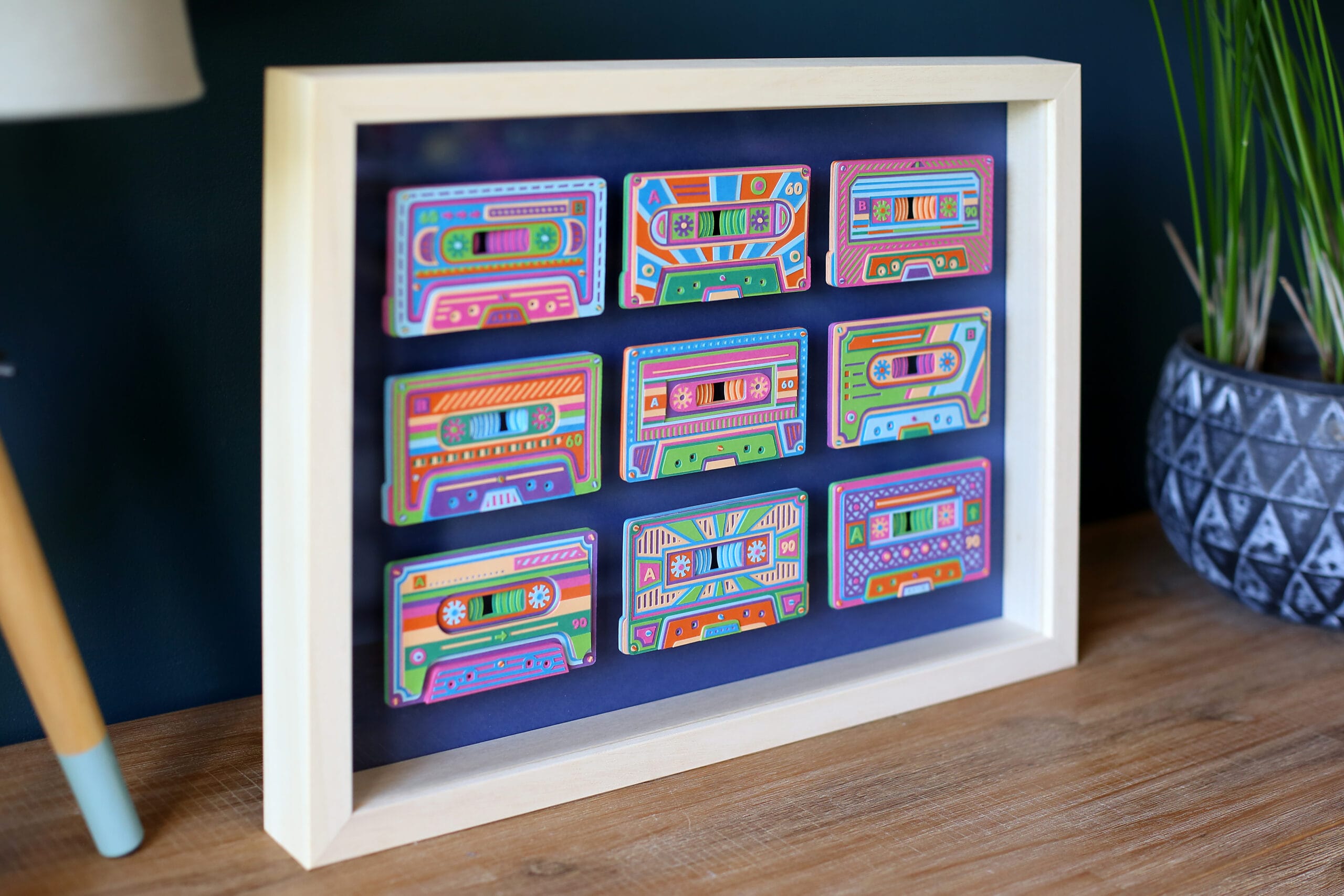 a set of colorful cassette tapes made from paper, in a white frame