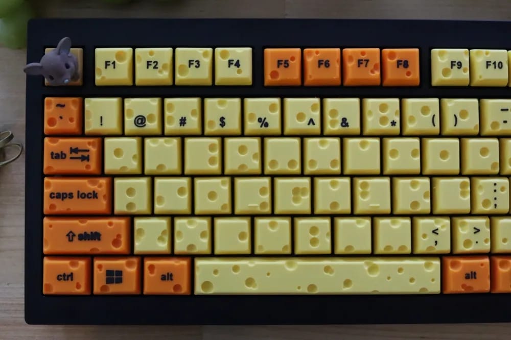 a part of a keyboard with key covers shaped like cheese and a charcuterie board