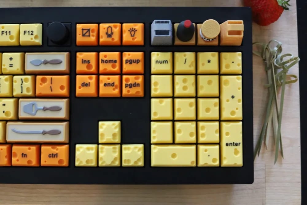a part of a keyboard with key covers shaped like cheese and a charcuterie board