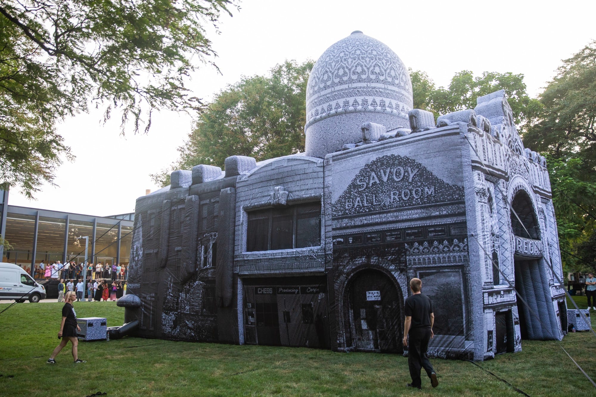 people walk around a large, inflatable building with signs on the side