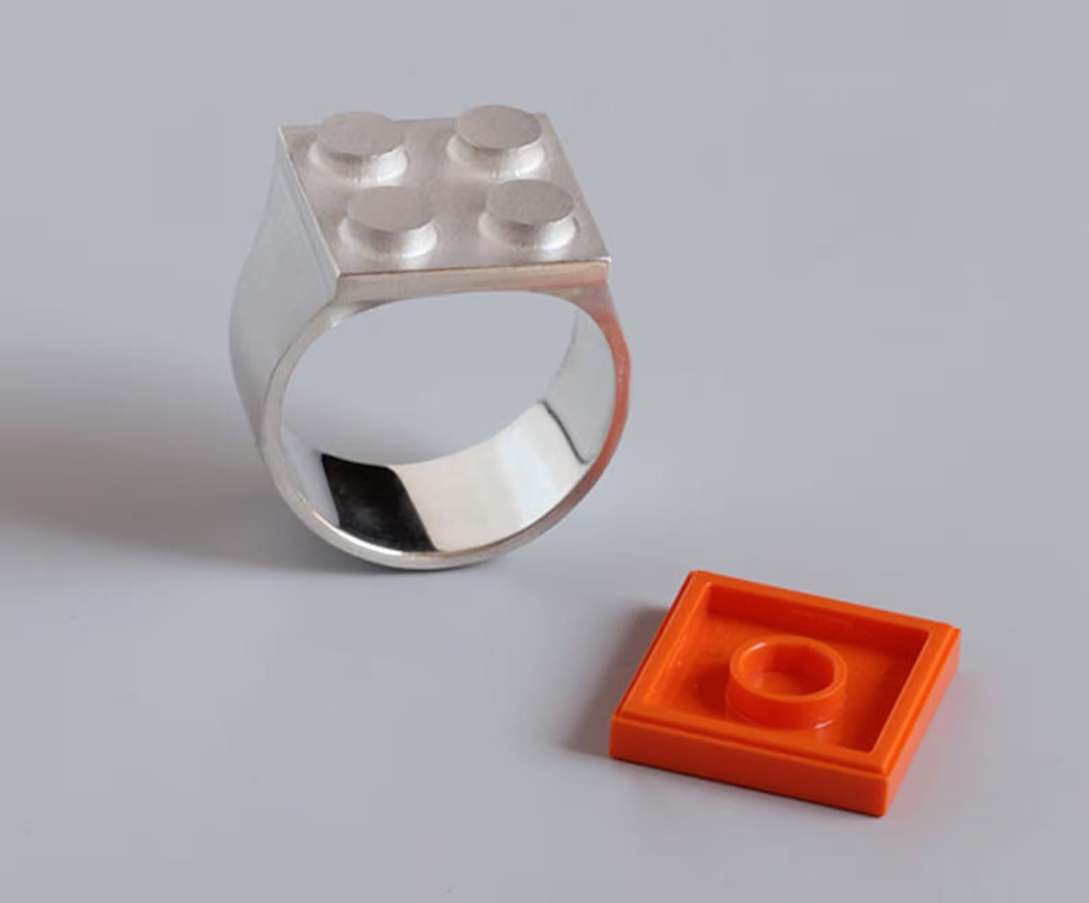 a sterling silver ring designed by Studio GOGO with an orange LEGO brick that fits on top