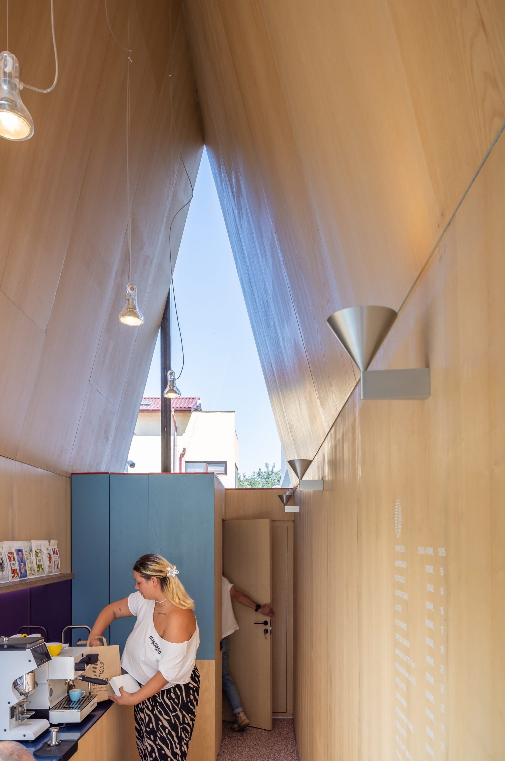 the interior of a small, contemporary cafe with a large triangular window