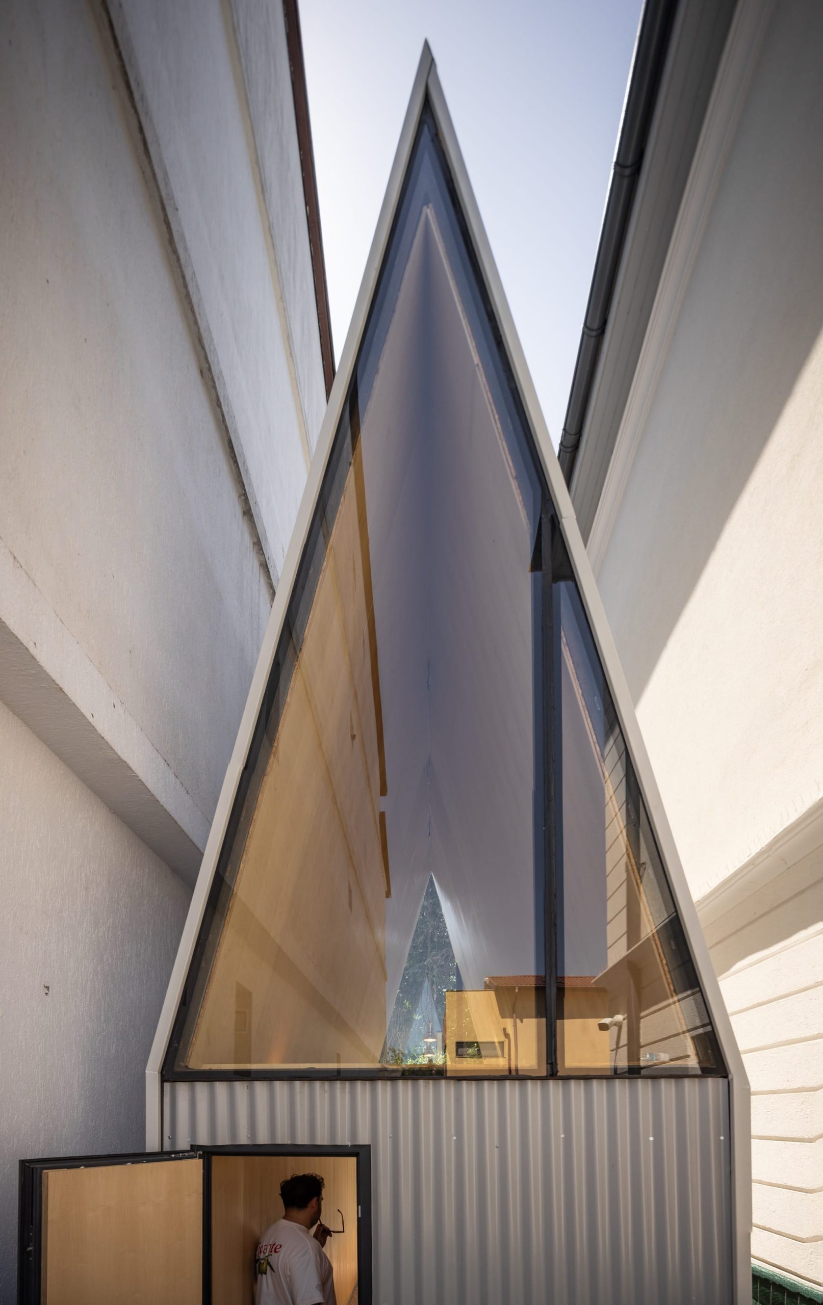a detail of the exterior of a small, contemporary cafe designed by Vinklu, with a large triangular window