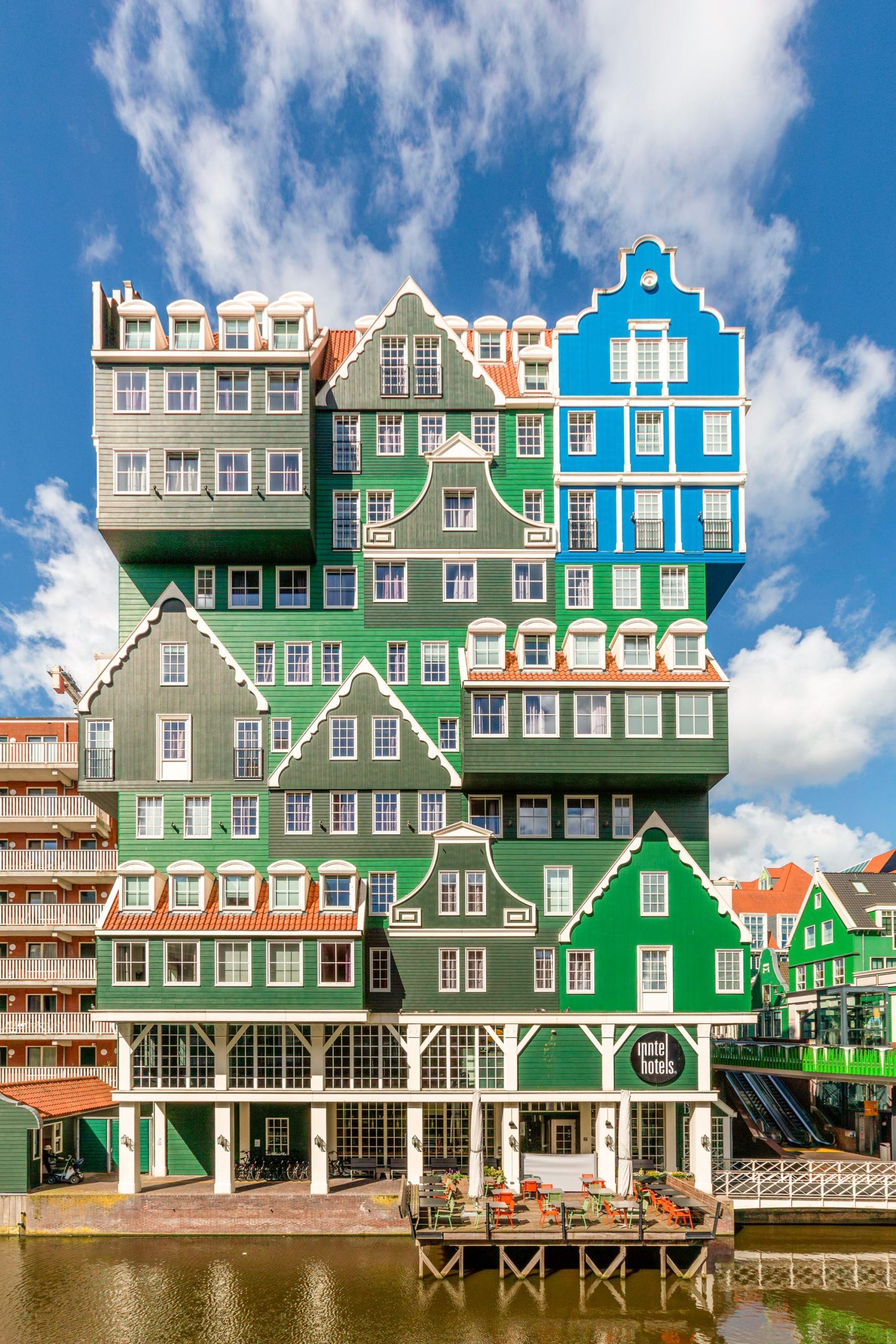 a fanciful, tall apartment building with a facade that looks like numerous stacked European facades in green and blue