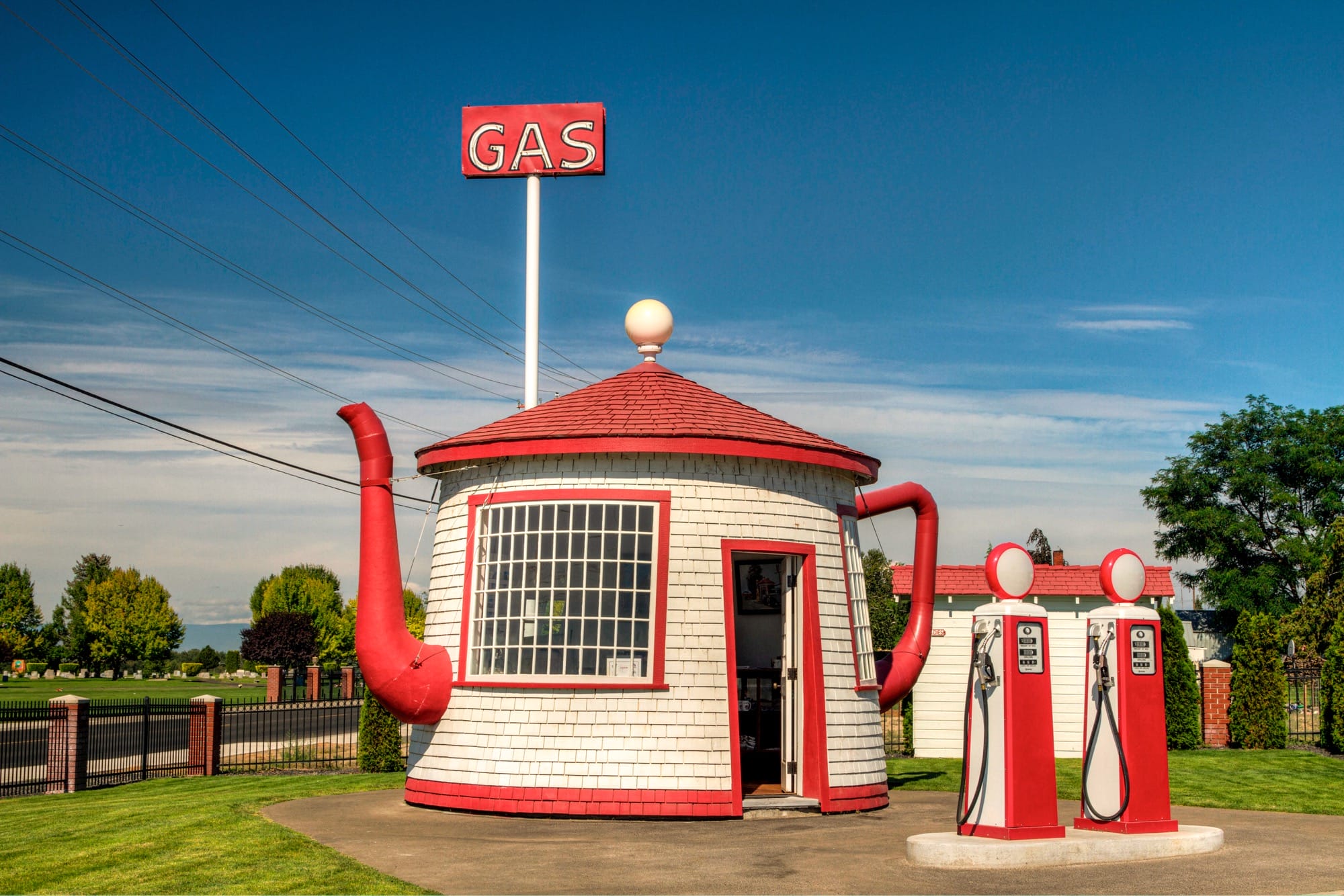 a tiny vintage service station shaped like a red-and-white teapot