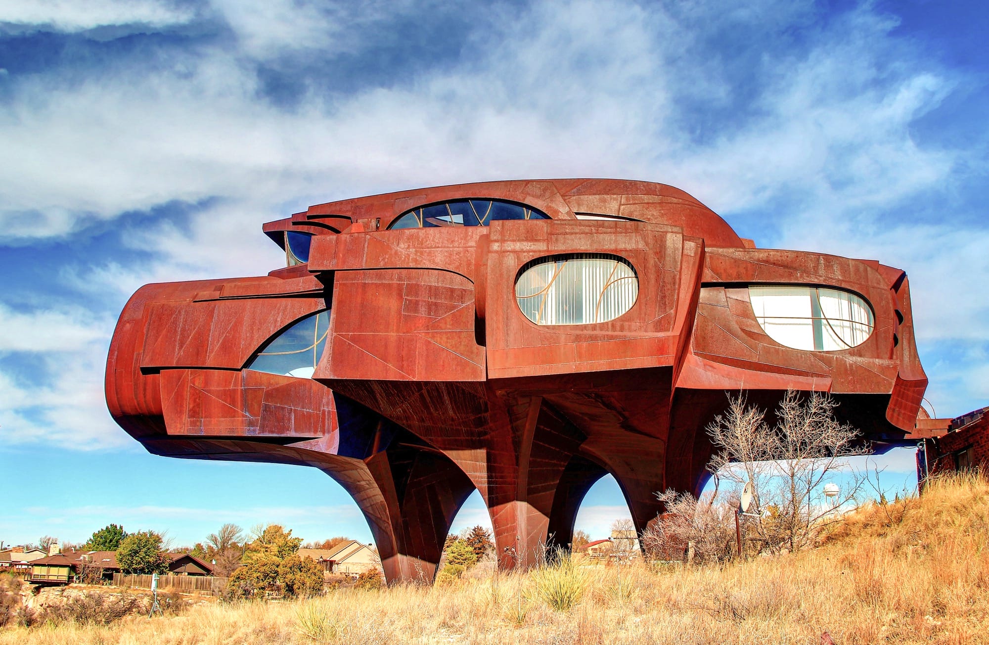 a futuristic, amorphous, rust-colored home that stands on sculptural posts