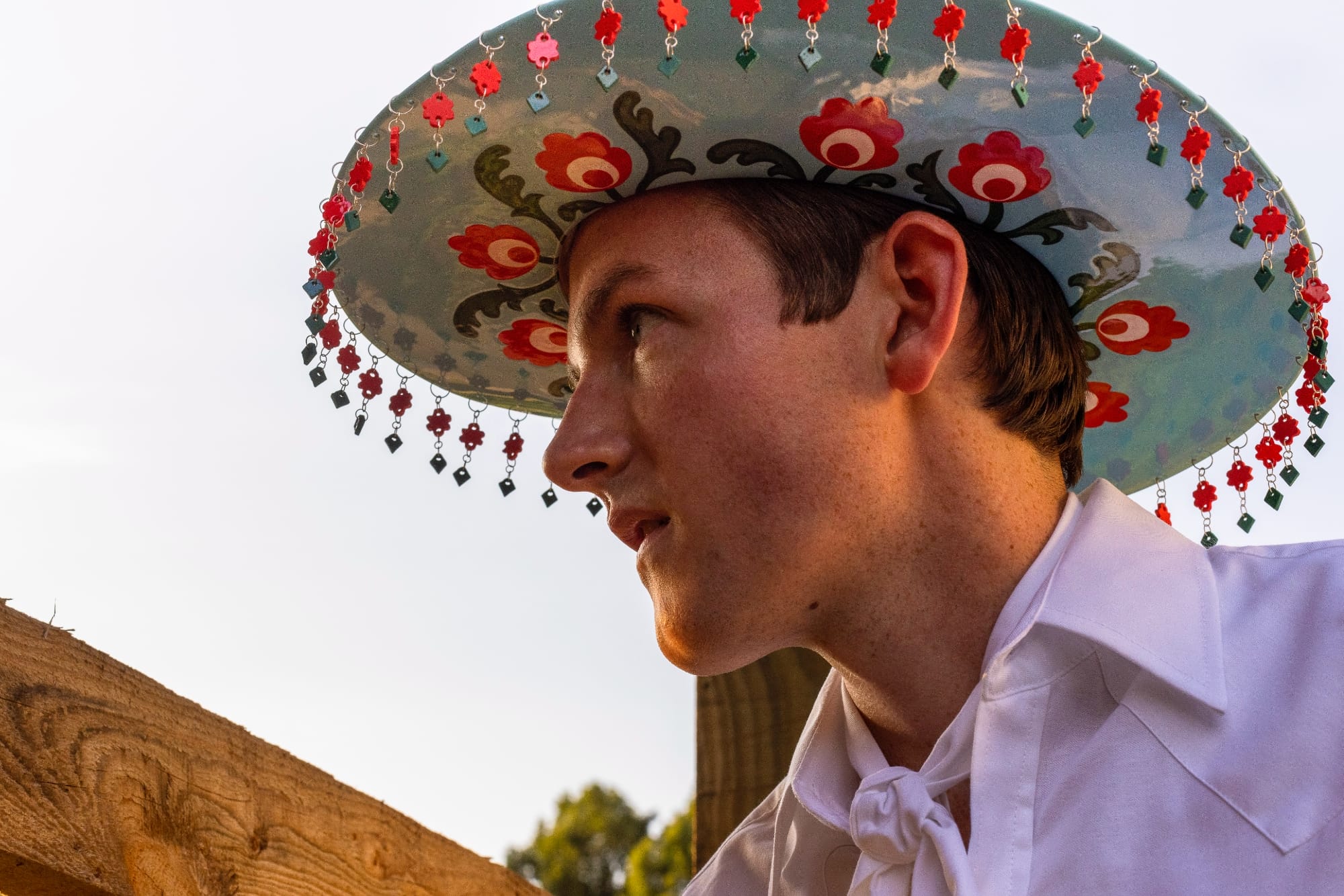 Shae Bishop wears a floral cowboy hat with red tassels on the edge of the brim