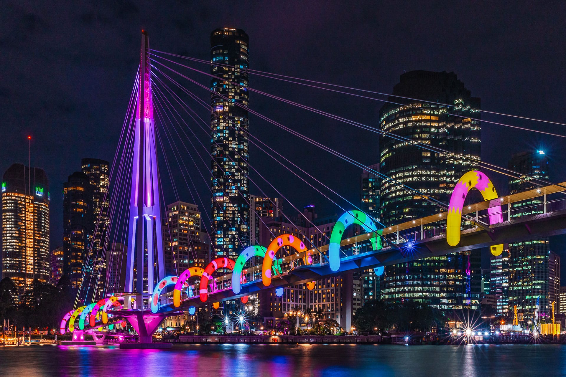 colorful, inflatable arches by Craig & Karl are installed on a long bridge in Bisbrane, illuminated at night