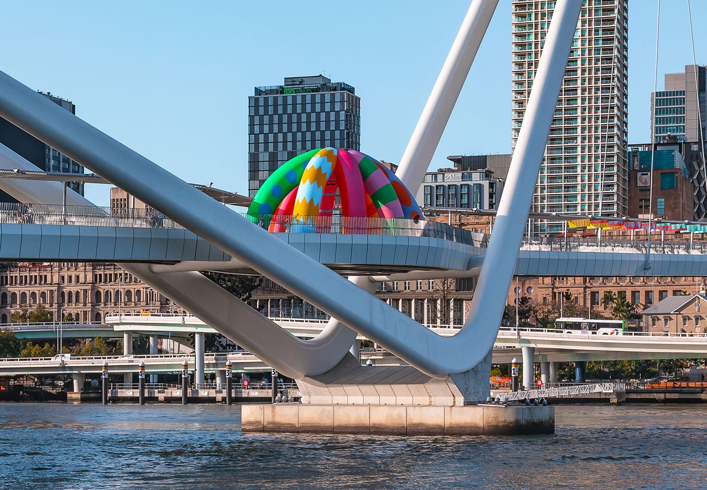 a colorful, inflatable installation on a Birsbane bridge by Craig & Karl of crayon-like shapes with expressive faces