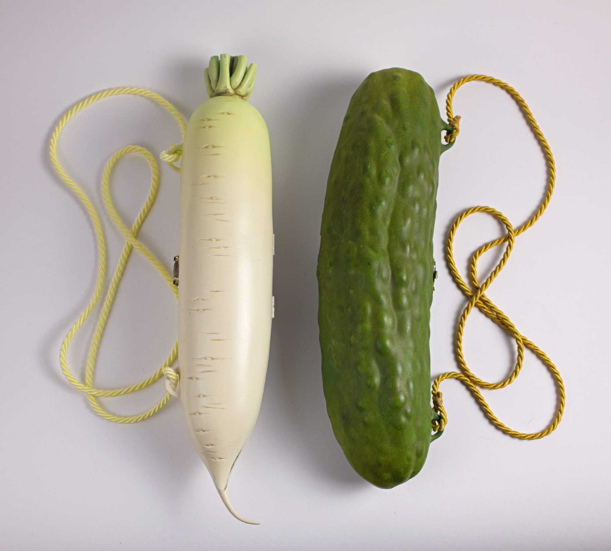 two sculptural handbags by Paolo Puck shaped like a radish and a pickle