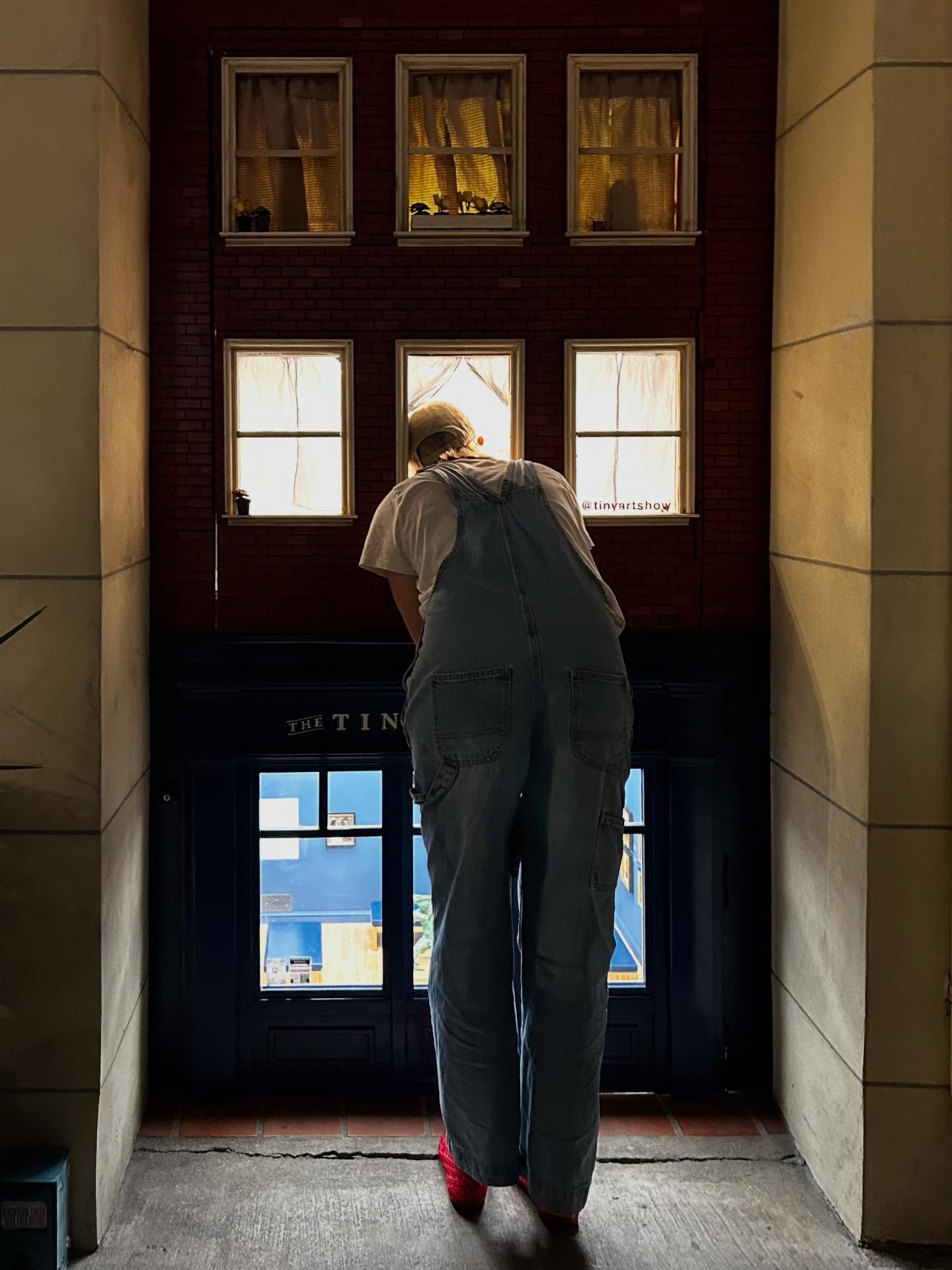 a person looks inside a 1/6-scale art gallery in a disused stairwell