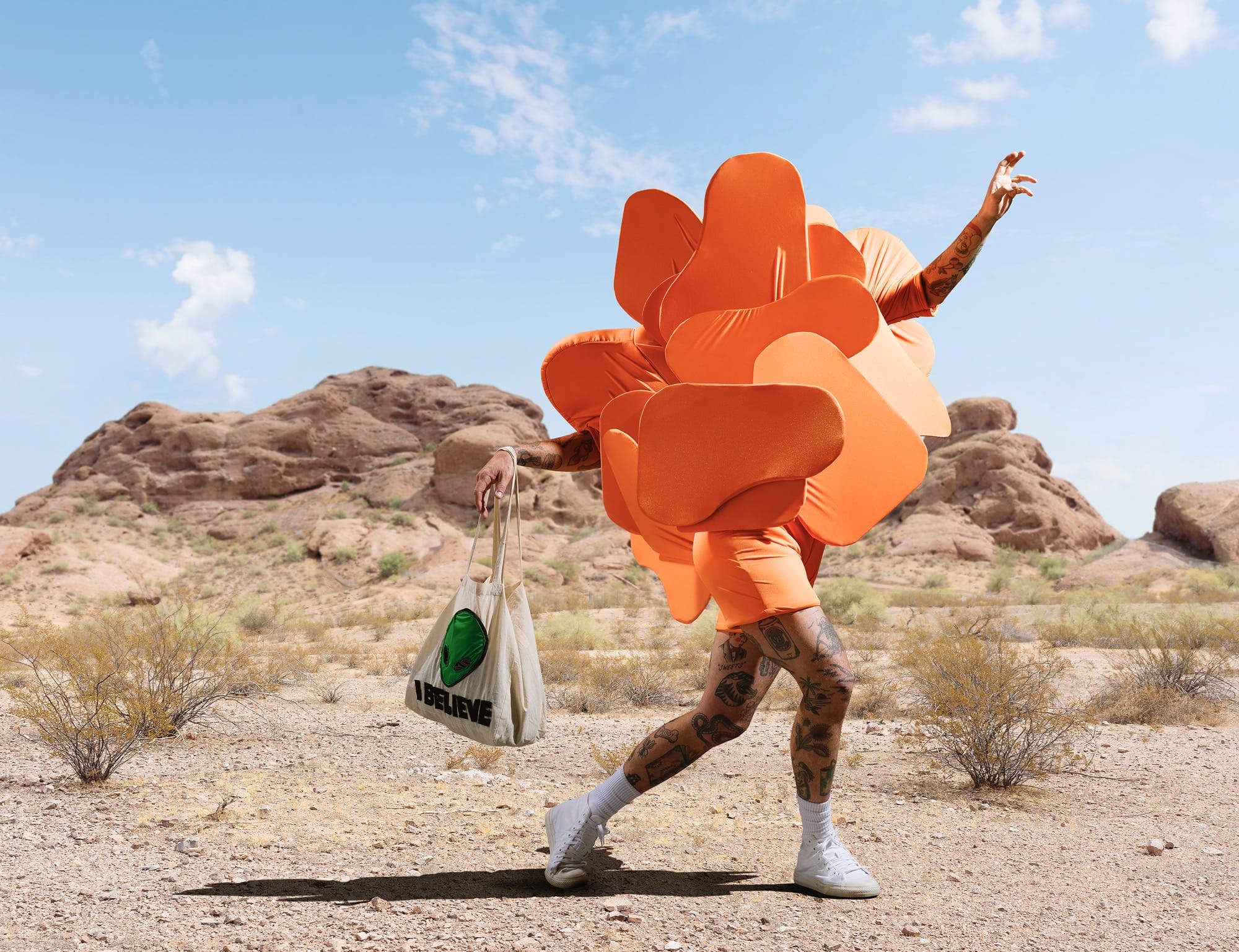 a photograph by Gerwyn Davies of a brightly colored abstract costume obscuring the top half of his body in a desert landscape
