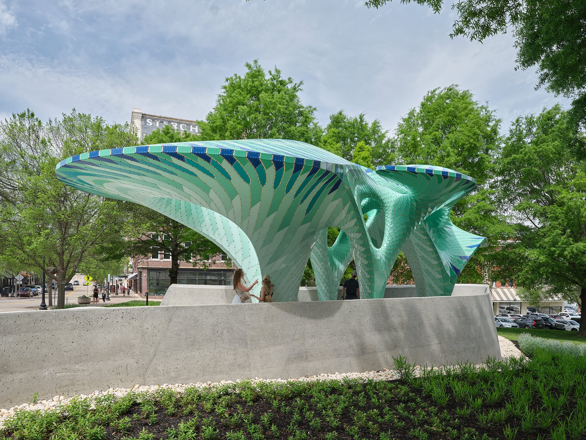 a contemporary, teal-colored pavilion designed by Marc Fornes/THEVERYMANY in a public square in Knoxville, Tennessee