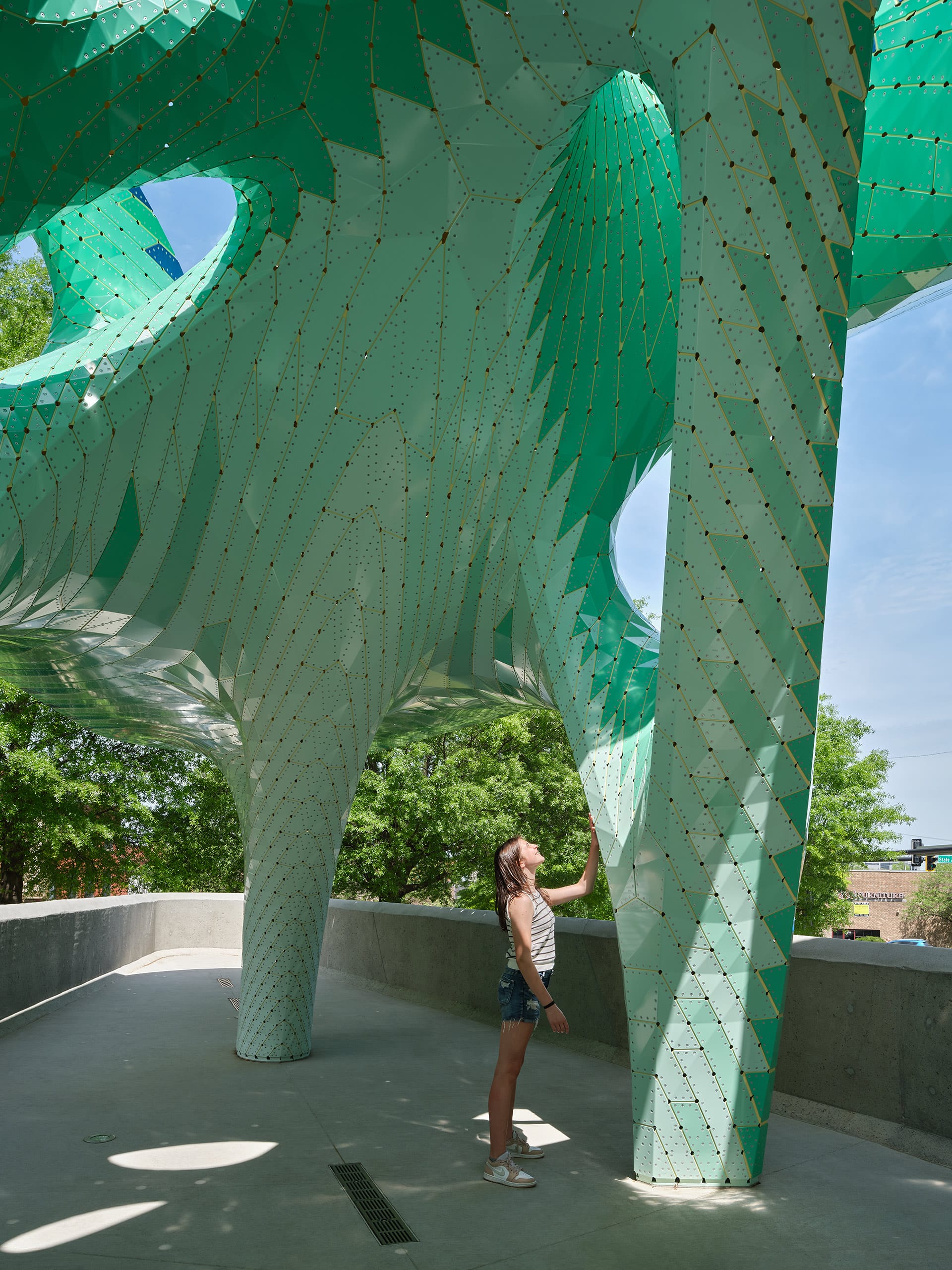a detail of a contemporary, teal-colored pavilion designed by Marc Fornes/THEVERYMANY in a public square in Knoxville, Tennessee