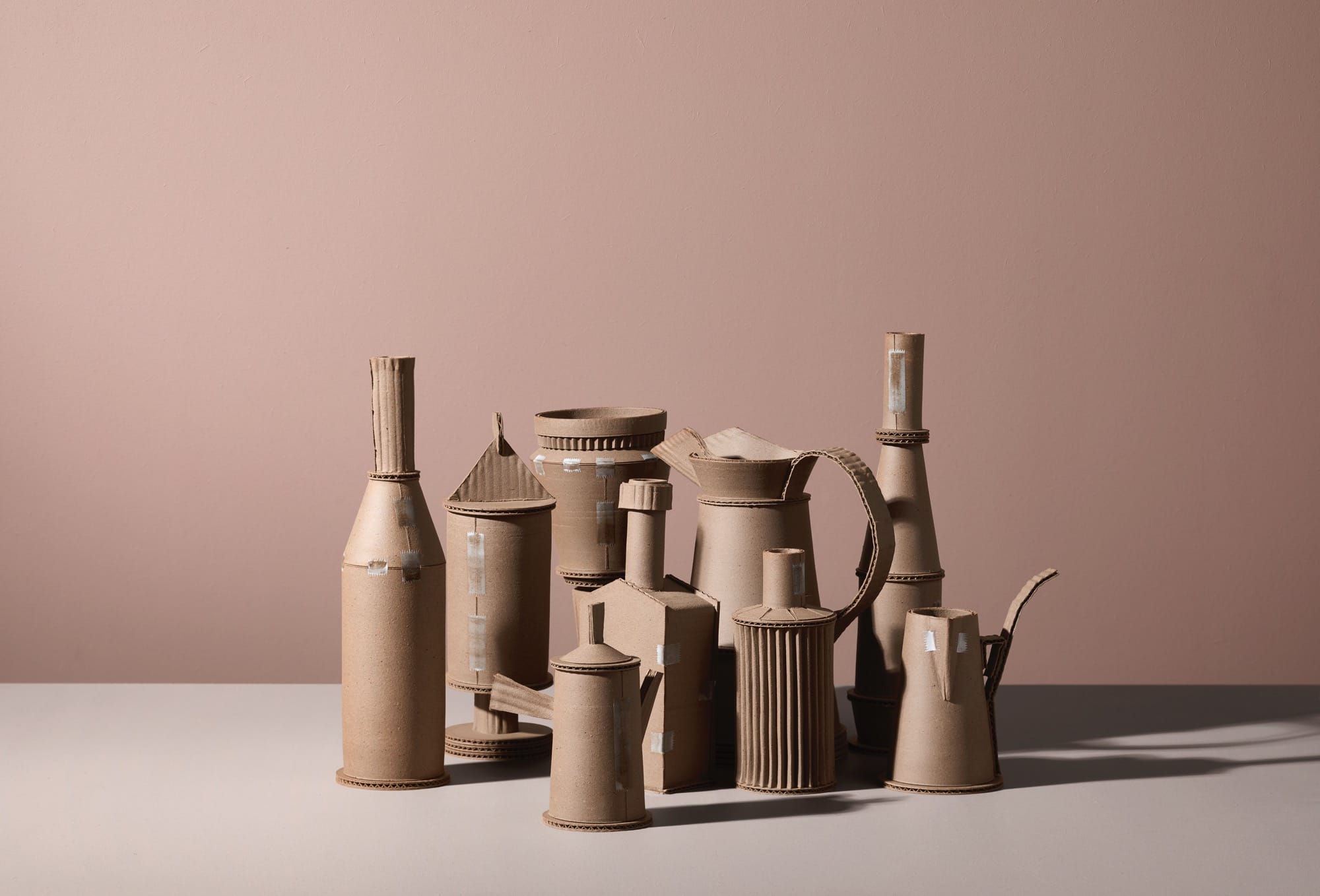 a series of ceramic vessels by Jacques Monneraud that resemble cardboard with tape, arranged to mimic a painting by Giorgio Morandi