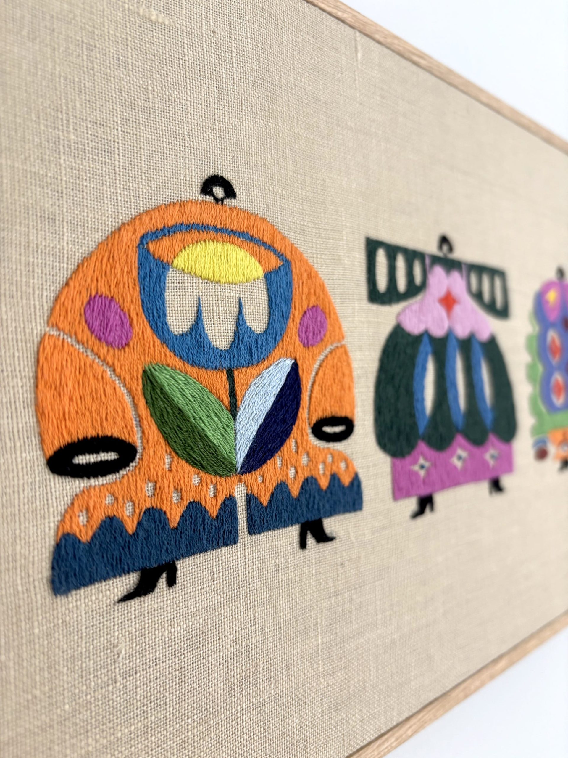 a detail of an embroidered artwork by Irene Saputra of four colorful, patterned, symmetrical, abstractly shaped figures